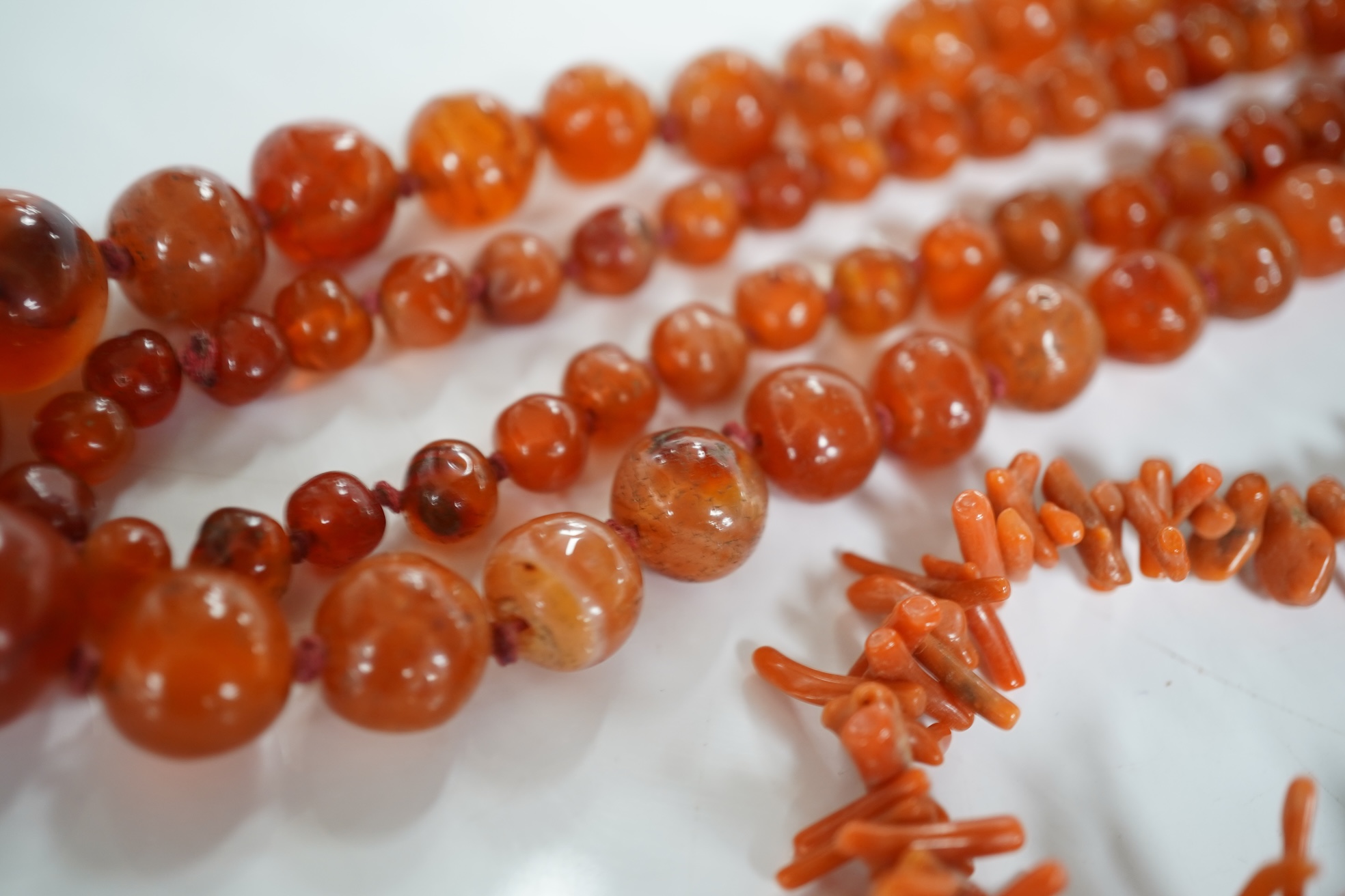 A micromosaic brooch and a group of bead necklaces, comprising: a micromosaic brooch depicting the Forum, length 4.6cm; together with a carnelian bead necklace; a coral branch necklace; and a green glass bead necklace